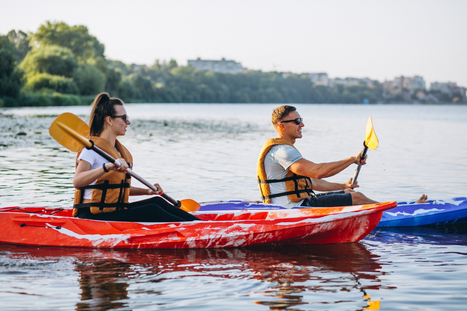 Couple kayaking on a calm river wearing life jackets during a scenic outdoor adventure in Goa
